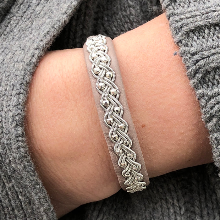 A handcrafted bracelet with round silver beads and a reindeer antler button, displayed on a wrist.