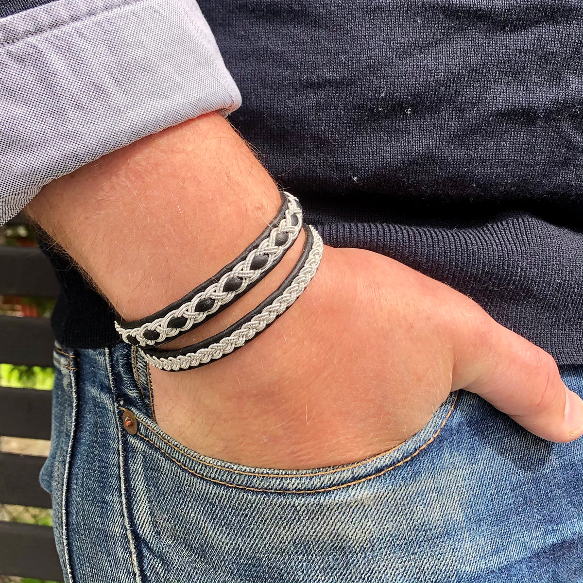 A person wearing a stylish silver and black braided bracelet with a reindeer antler button.